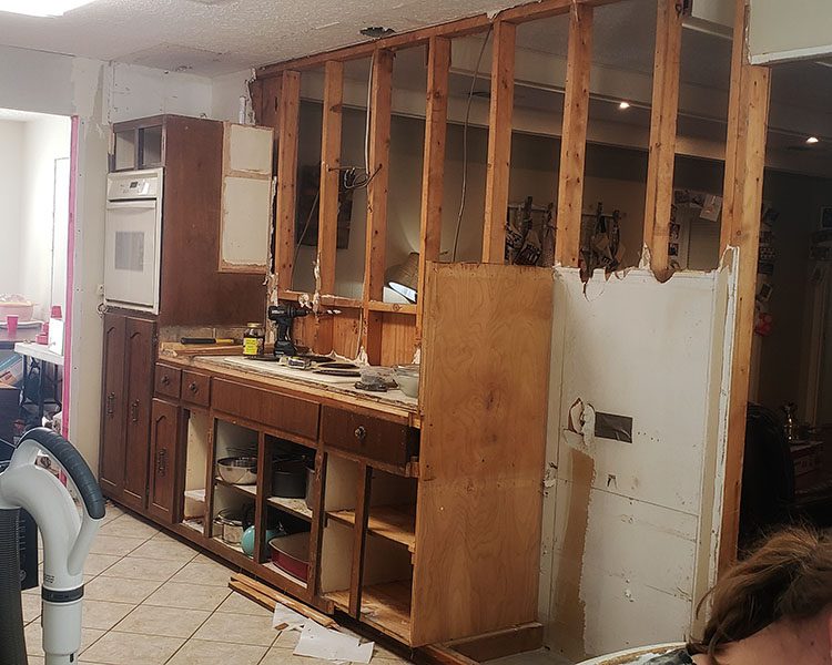 partially torn out kitchen cabinets and wall